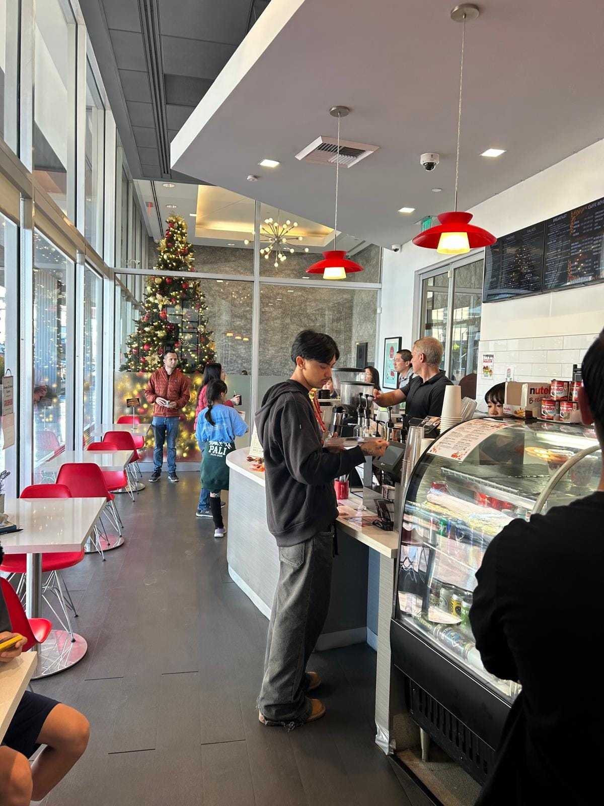 Cafe with people ordering coffee, festive decorations, and a Christmas tree.